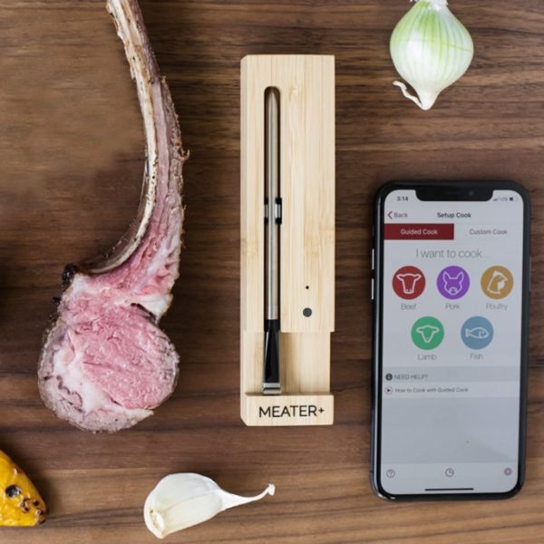 Termometr Meater + w drewnianym etuti wraz z telefonem i włączoną aplikacją.